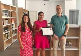 Carlos Caro, alcalde arroyano, y la concejala Leticia Carreo, junto a la responsable de la biblioteca, Esther Cordero, que muestra el premio.