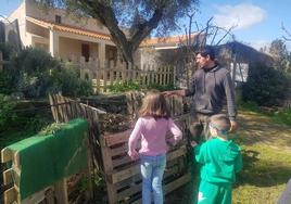 Chemo Araujo enseñando el compostaje agrario de biorresiduos en la Huerta la Mangurria a dos niños.