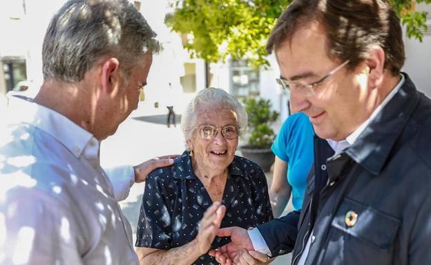 Guillermo Fernández Vara y Elías López saludando ayer a una vecina. 