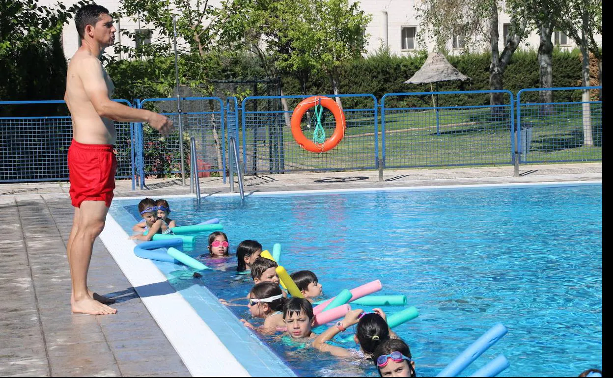 Uno de los monitores enseña a los niños a nadar en la piscina municipal. 