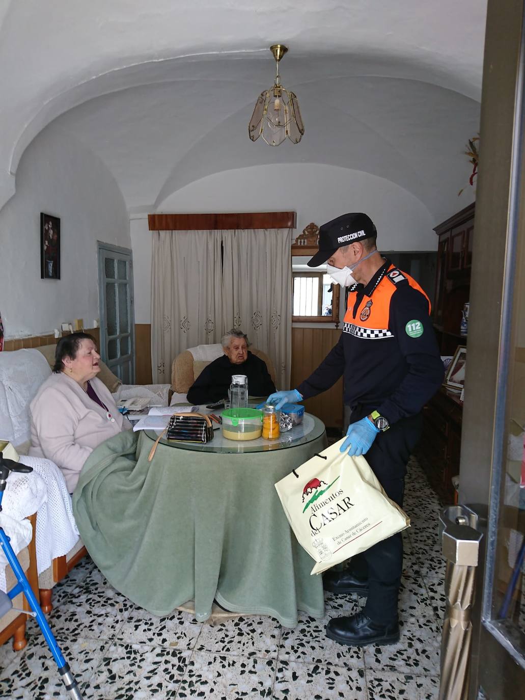 Un voluntario de Protección Civil, ayer, entregando comida a dos vecinas. 