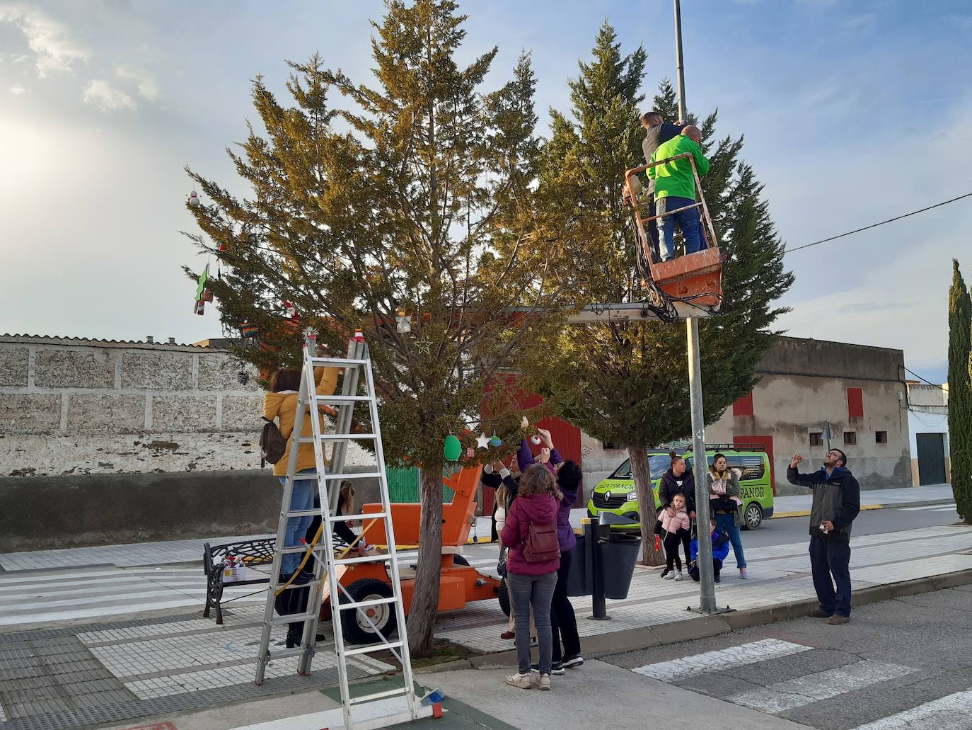 Algunos padres decoran el árbol de la puerta principal de Primaria con adornos realizados por los alumnos. 