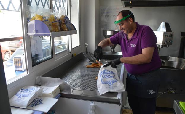 Ángel prepara una bolsa de churros protegido con pantalla y guantes. 