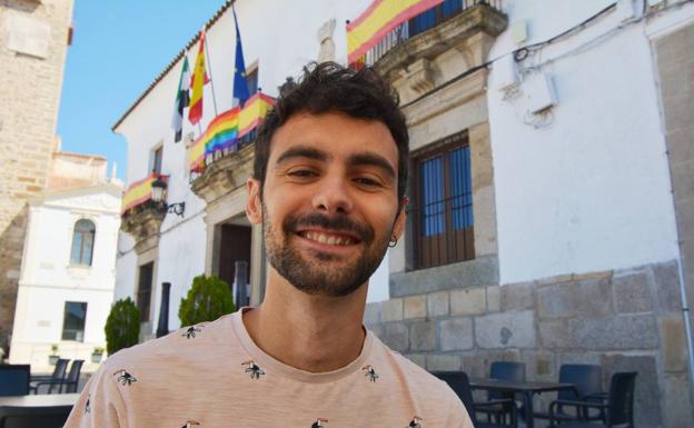 Pedro Galván Ardila bajo la bandera LGTBI+ que cuelga del Ayuntamiento 