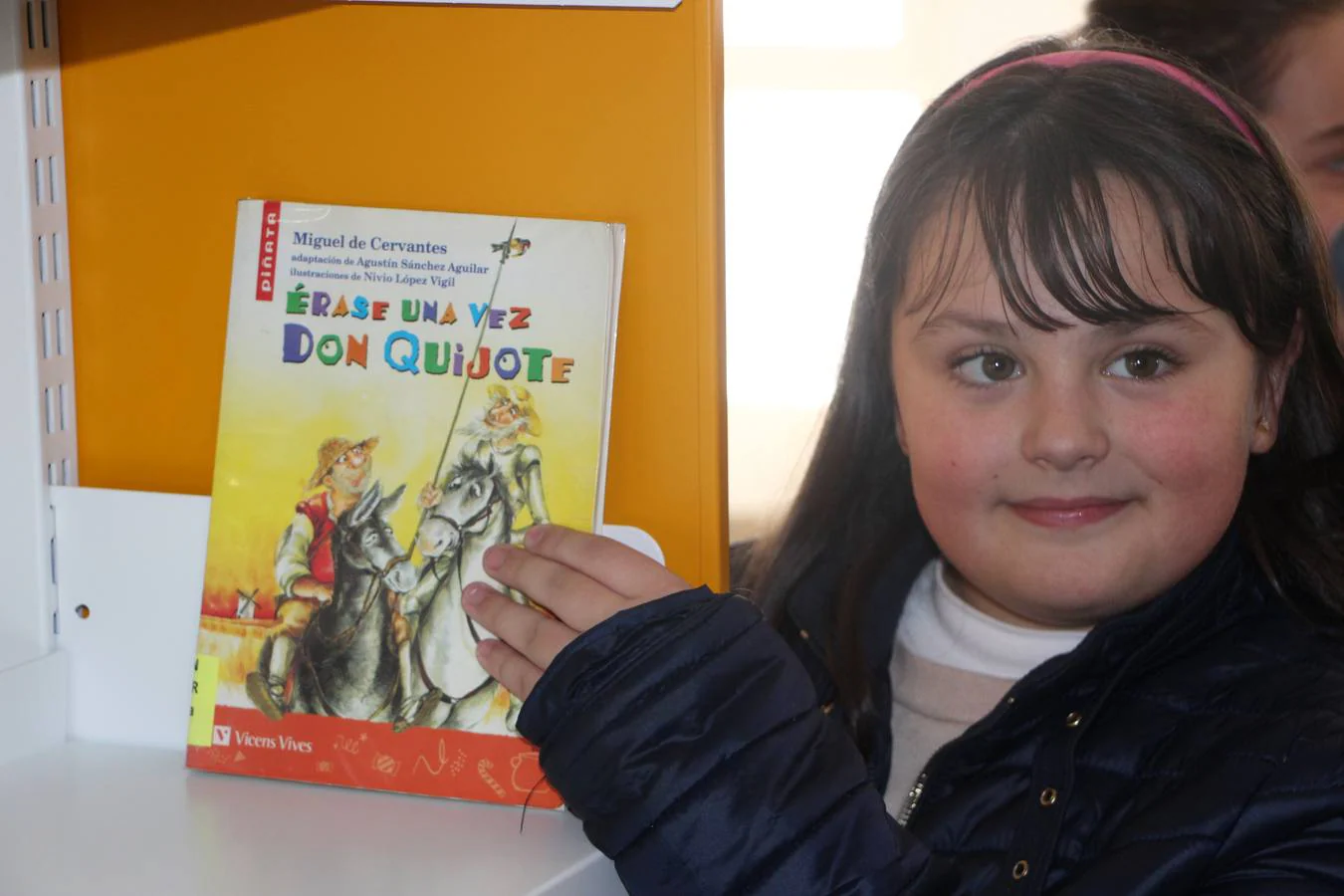 La niña Lidia muestra el primer libro que llega a la nueva biblioteca Eugenio Frutos.