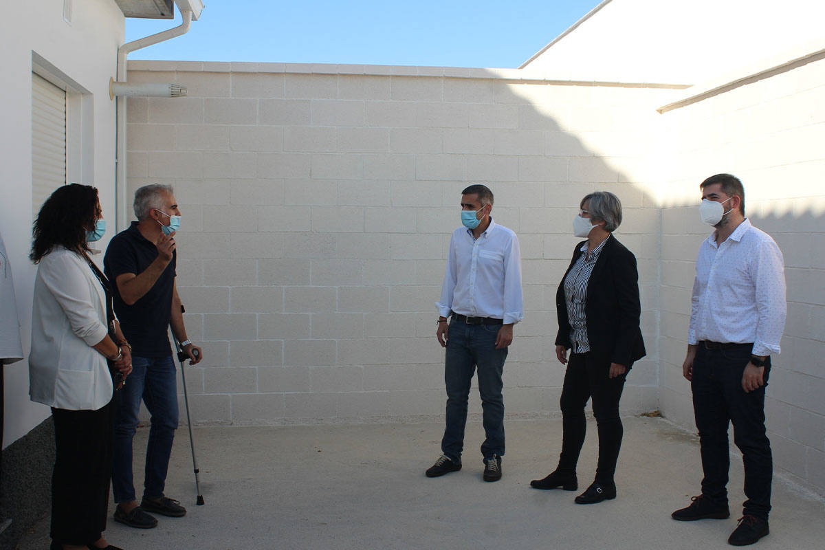 Un vecino con muletas explicando a las autoridades en el patio de su casa nueva.
