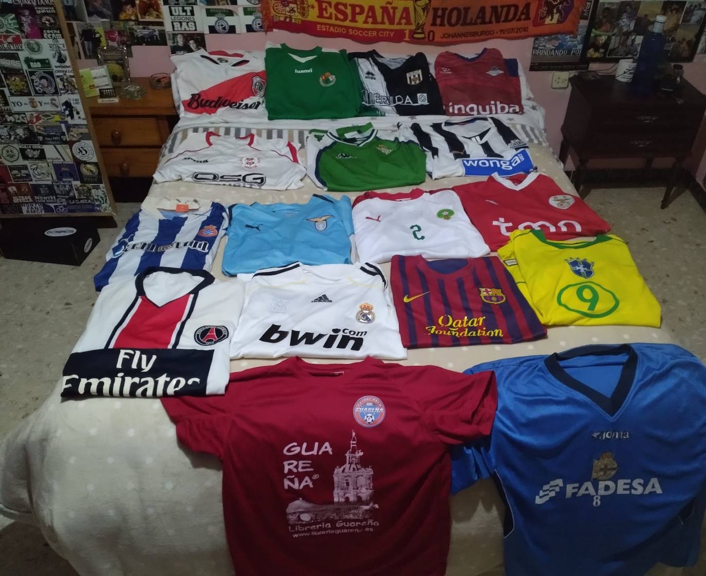 Camisetas de todos los colores y equipos sobre su cama.