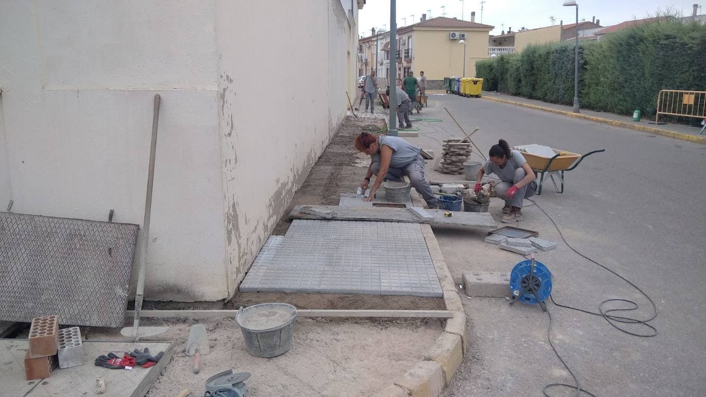 Mujeres y hombres se afanan en aprender la albañilería en la escuela.