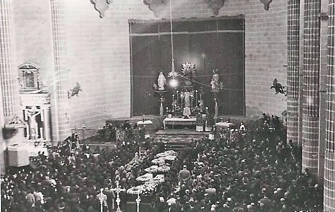 Iglesia abarrotada con féretros en el pasillo y la iglesia sin retablo mayor.