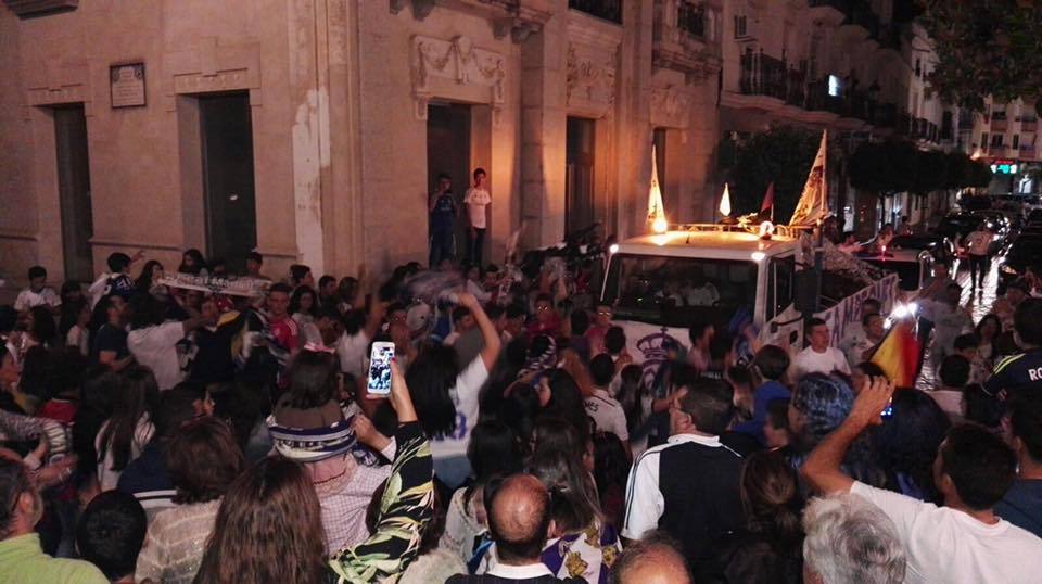 Caravana de aficionados madridistas a su paso por la plaza de España.