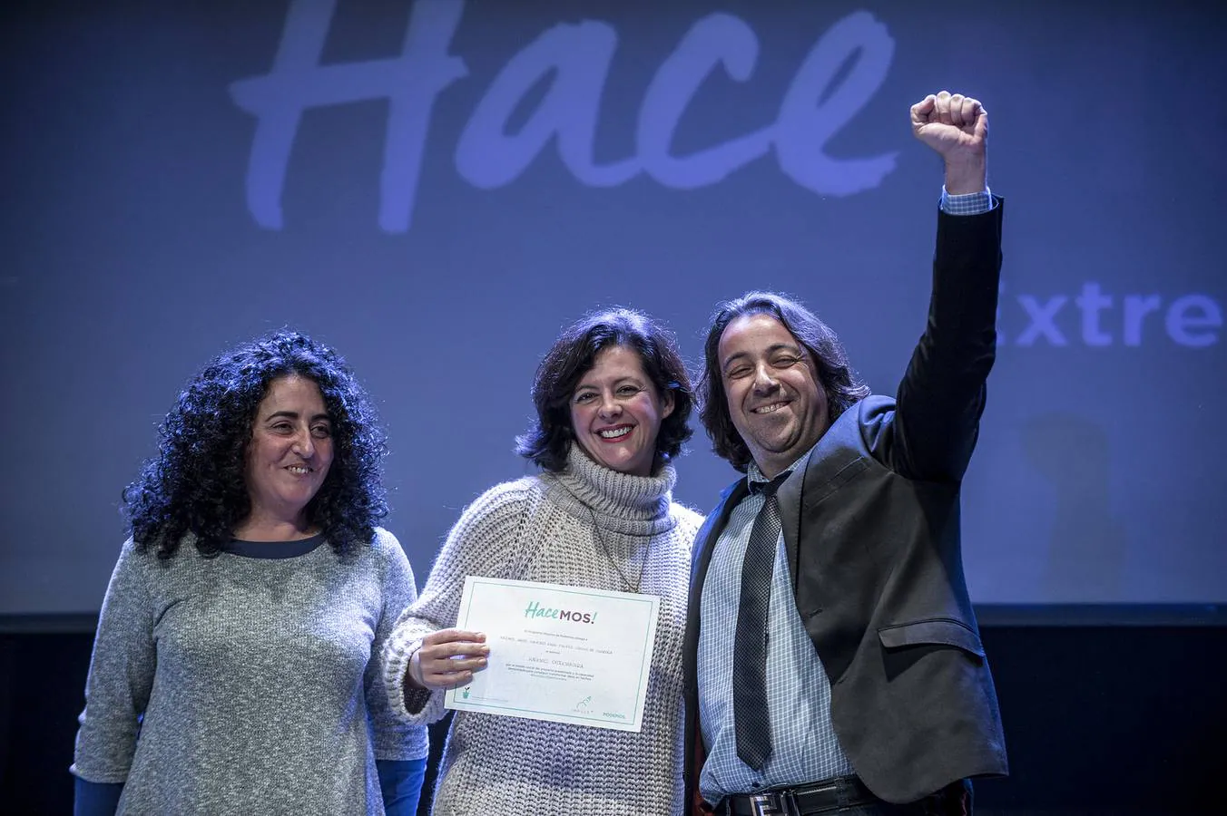 Eva García muestra el premio 'Hacemos!' (en el centro de la imagen), y José Luis Morcillo, eufórico, lev