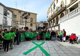 Los asistentes a la concentración detrás del gran lazo verde desplegado en la Plaza Mayor jaraiceña.