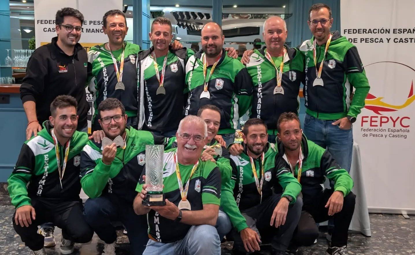 Carlos Labrador, de pie, el primero por la derecha, con el resto del equipo mostrando las medallas y trofeo.