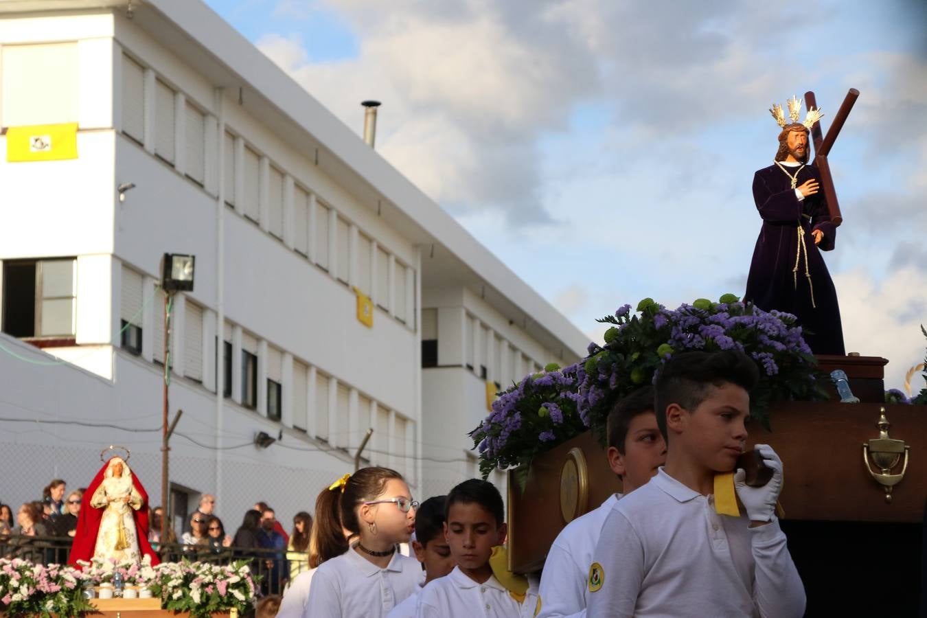 El Colegio «El Rodeo» celebró, ayer, una nueva edición de su Semana Santa infantil que, año tras año, se consolida como una de las citas imprescindibles del calendario cofrade jerezano. La iniciativa cuenta con la implicación de alumnos, padres y profesores, y muestra cómo los más pequeños comienzan a interiorizar los roles propios de quienes participan y hacen posible la Semana Santa del municipio: costaleros, capataces, nazarenos, agrupaciones musicales, mujeres ataviadas con mantilla negra, escoltas romanas, etc. La Agrupación Musical «Nuestro Padre Jesús Nazareno» y la Agrupación Musical «Maestro Sousa» de la OJE acompañaron con sus sones esta entrañable recreación.