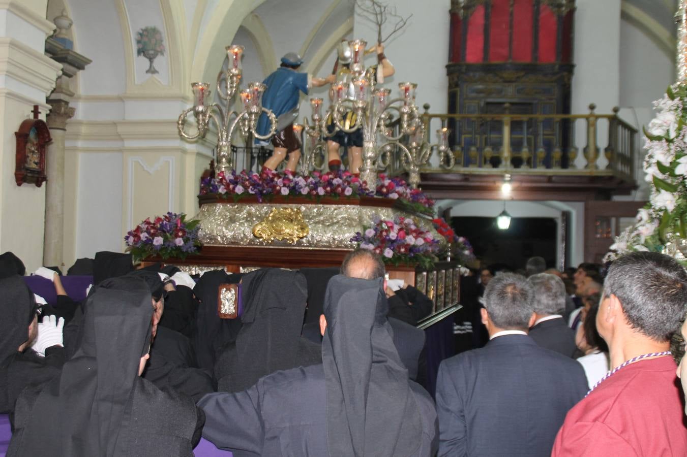 Las emociones llenaron también anoche la ermita de Los Santos Mártires, donde se quedaron guardados todos los afanes, las ilusiones y la devoción que no pudieron tener reflejo en la procesión de las colas largas, La Cofradía del Señor Coronado de Espinas decidió no salir ante la adversidad de la climatología y en el interior de este pequeño templo se vivieron momentos de gran emotividad.La Guardia Civil de Jerez de los Caballeros rindió honores a s Madrina, María Santísima de la Amargura. Los sones de las bandas y agrupaciones que iban a participar en el desfile procesional expandieron su eco desde el Llano de los Mártires para acompañar a los costaleros de cada uno de los tres Pasos, que fueron mecidos a su compás. El jovencísimo saetero Julián Jaramillo, de tan solo 12 años y natural de Segura de León, hizo vibrar a los presentes con su saeta al Coronado.Y entre las oraciones del párroco, Antonio María Rejano y los sacerdotes que le acompañaron, asomaron también las lágrimas.El momento más emotivo se vivió con el sentido homenaje a Manuel Labrador González, Manolo 'Cornelio' a quien Marisa Sánchez, en nombre de la junta de gobierno de la Cofradía del Señor Coronado, dedicó palabras llenas de afecto y reconocimiento, destacando su condición de «trabajador sin igual», su carácter innovador, su generosidad, sus consejos a jóvenes y mayores en el seno de esta Cofradía de la que dijo, «es piedra angular» y su extraordinaria labor. Manuel recibió un libro y una precioso cartel realizada por José Tomás Pérez Indiano, a semejanza del que hace tres años anunció la Semana Santa Jerezana. Emocionado, Manuel agradeció el cariño y dedicó este homenaje a su familia y a todas las madres.