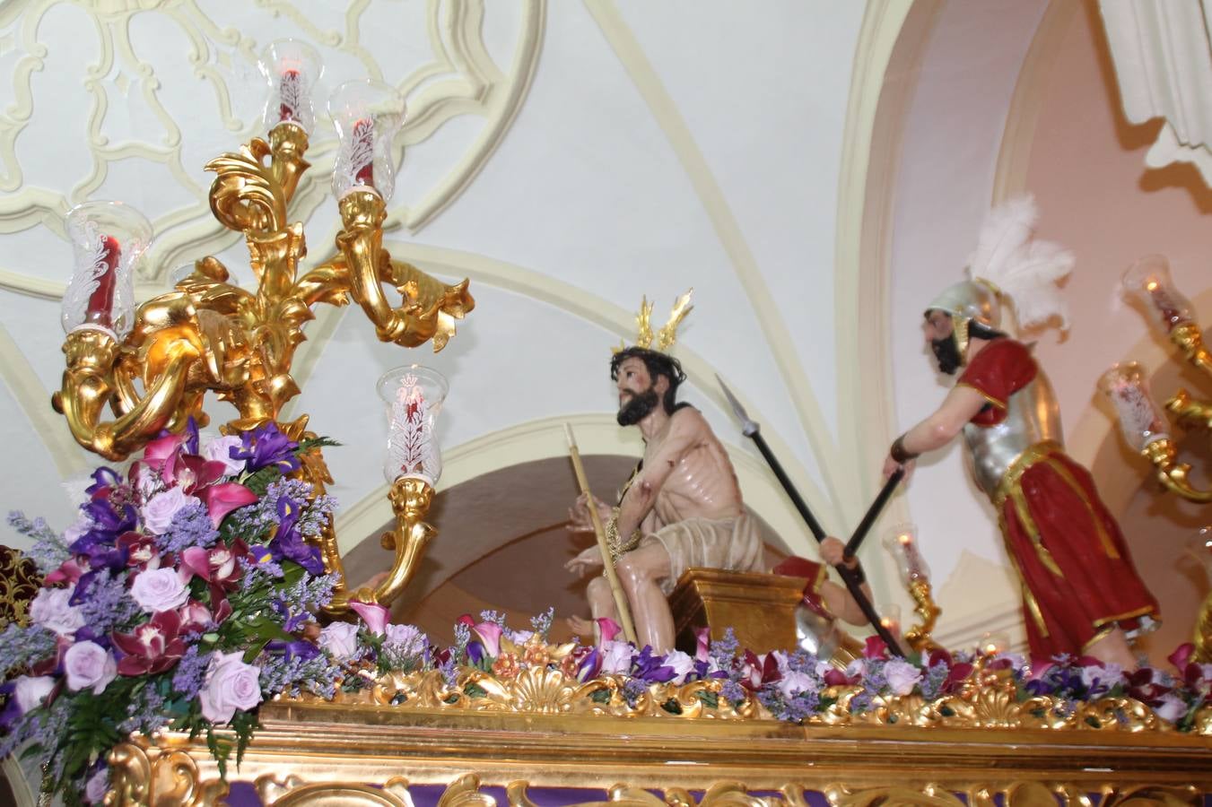 Las emociones llenaron también anoche la ermita de Los Santos Mártires, donde se quedaron guardados todos los afanes, las ilusiones y la devoción que no pudieron tener reflejo en la procesión de las colas largas, La Cofradía del Señor Coronado de Espinas decidió no salir ante la adversidad de la climatología y en el interior de este pequeño templo se vivieron momentos de gran emotividad.La Guardia Civil de Jerez de los Caballeros rindió honores a s Madrina, María Santísima de la Amargura. Los sones de las bandas y agrupaciones que iban a participar en el desfile procesional expandieron su eco desde el Llano de los Mártires para acompañar a los costaleros de cada uno de los tres Pasos, que fueron mecidos a su compás. El jovencísimo saetero Julián Jaramillo, de tan solo 12 años y natural de Segura de León, hizo vibrar a los presentes con su saeta al Coronado.Y entre las oraciones del párroco, Antonio María Rejano y los sacerdotes que le acompañaron, asomaron también las lágrimas.El momento más emotivo se vivió con el sentido homenaje a Manuel Labrador González, Manolo 'Cornelio' a quien Marisa Sánchez, en nombre de la junta de gobierno de la Cofradía del Señor Coronado, dedicó palabras llenas de afecto y reconocimiento, destacando su condición de «trabajador sin igual», su carácter innovador, su generosidad, sus consejos a jóvenes y mayores en el seno de esta Cofradía de la que dijo, «es piedra angular» y su extraordinaria labor. Manuel recibió un libro y una precioso cartel realizada por José Tomás Pérez Indiano, a semejanza del que hace tres años anunció la Semana Santa Jerezana. Emocionado, Manuel agradeció el cariño y dedicó este homenaje a su familia y a todas las madres.