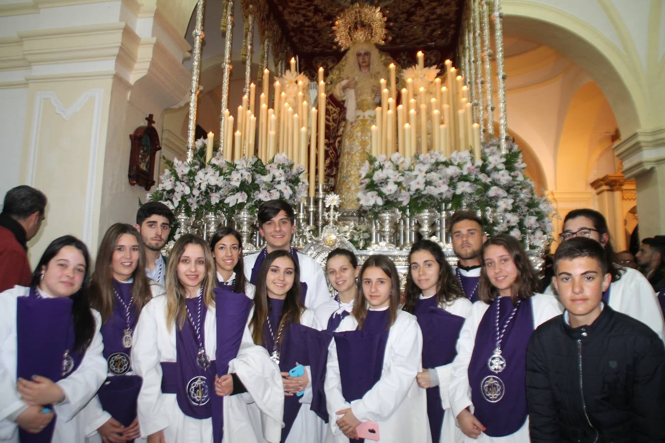 Las emociones llenaron también anoche la ermita de Los Santos Mártires, donde se quedaron guardados todos los afanes, las ilusiones y la devoción que no pudieron tener reflejo en la procesión de las colas largas, La Cofradía del Señor Coronado de Espinas decidió no salir ante la adversidad de la climatología y en el interior de este pequeño templo se vivieron momentos de gran emotividad.La Guardia Civil de Jerez de los Caballeros rindió honores a s Madrina, María Santísima de la Amargura. Los sones de las bandas y agrupaciones que iban a participar en el desfile procesional expandieron su eco desde el Llano de los Mártires para acompañar a los costaleros de cada uno de los tres Pasos, que fueron mecidos a su compás. El jovencísimo saetero Julián Jaramillo, de tan solo 12 años y natural de Segura de León, hizo vibrar a los presentes con su saeta al Coronado.Y entre las oraciones del párroco, Antonio María Rejano y los sacerdotes que le acompañaron, asomaron también las lágrimas.El momento más emotivo se vivió con el sentido homenaje a Manuel Labrador González, Manolo 'Cornelio' a quien Marisa Sánchez, en nombre de la junta de gobierno de la Cofradía del Señor Coronado, dedicó palabras llenas de afecto y reconocimiento, destacando su condición de «trabajador sin igual», su carácter innovador, su generosidad, sus consejos a jóvenes y mayores en el seno de esta Cofradía de la que dijo, «es piedra angular» y su extraordinaria labor. Manuel recibió un libro y una precioso cartel realizada por José Tomás Pérez Indiano, a semejanza del que hace tres años anunció la Semana Santa Jerezana. Emocionado, Manuel agradeció el cariño y dedicó este homenaje a su familia y a todas las madres.