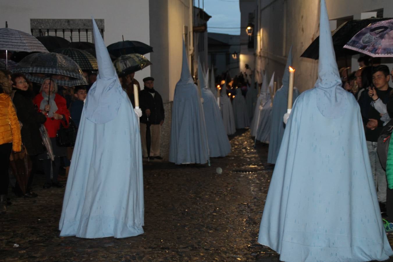 La lluvia que durante las primeras horas de la tarde se contuvo, hizo acto de presencia nada más asomarse a la calle la procesión de las túnicas celestes, que organiza la Archicofrafía del Santísimo Sacramento. Todas las emociones se vieron frustradas y el templo de San Bartolomé fue refugio para el sentimiento de quienes anhelaban acompañar esta estación de penitencia en la que se representa el momento de la institución de la Santa Cena, que junto al de Jesús ante Pilatos, fueron los únicos que realizaron su salida de la iglesia patronal. El Cristo de la Piedad, imagen impresionante en el itinerario de la Semana Santa jerezana, y la hermosa Virgen de la Paza, se quedaron dentro.Los sones de las Agruaciones y bandas que iban a acompañar este desfile sonaron especiales para bailar estas dos imágenes y servir de consuelo, mientras brotaban lágrimas en los ojos de algunos niños que encuentran en esta Cofradía su bautismo nazareno. La oración también acompañó estos momentos de tristeza al tiempo tan especiales.