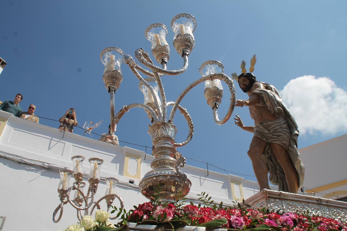 La luz y el gozo han puesto un gran broche a una Semana Santa, aciaga en sus momentos más intensos, a causa del mal tiempo que desde la noche del Miércoles y hasta el Viernes Santo trastocó en buena medida su desarrollo.Hoy el sol ha lucido en el cielo que como, cada Domingo de Resurrección, ha servido de Palio al hermoso Paso de la Virgen del Rosario, haciendo resplandecer, al tiempo, el momento culmen de esta celebración, el reencuentro en la Madre y el Hijo en la Fuente de los Santos, abarrotada de público. El momento ha sido emocionante, con los costaleros de la virgen y del Paso del Resucitado subiendo los brazos al cielo para representar el abrazo de ambas imágenes, ante la tradicional suelta de globos de ecolores y el estrépito de cornetas y tambores.La procesión ha seguido su curso hacia la Plaza de España, también muy concurrida, siendo en este escenario donde, miembros de Grupo Joven de la Cofradía del Coronado han regalado una petalada a la Virgen del Rosario. Ha sido un ofecimiento de la citada Cofradía que la noche del pasado Jueves no pudo obsequiar a su Virgen de la Amargura con esta lluvia de pétalos de rosas, a causa del mal tiempo.Así ha terminado la Semana Santa, incompleta para varias cofradías. La parte más amarga la han vivido la Cofradía del Señor Ecce-Homo que vió acortado su recorrido el Miércoles en una noche desapacible. También la Archicofradía del Santísimo Sacramento que apenas pudo asomarse a la calle y vió concentradas sus emociones en el templo patronal y la Cofradía del Señor Coronado de Espinas que también concentró el sentimieno y la devoción en la ermita de los Santos Mártires, viviendo momenos íntimos de gran emotividad. La Hermandad de la Esperanza Macarena brilló, sin embargo, en la Madrugá jerezana y la Cofradía de Nuestro Padre Jesús Nazareno derrochó fervor la tarde del Viernes en el interior de la iglesia visigoda de Santa María.