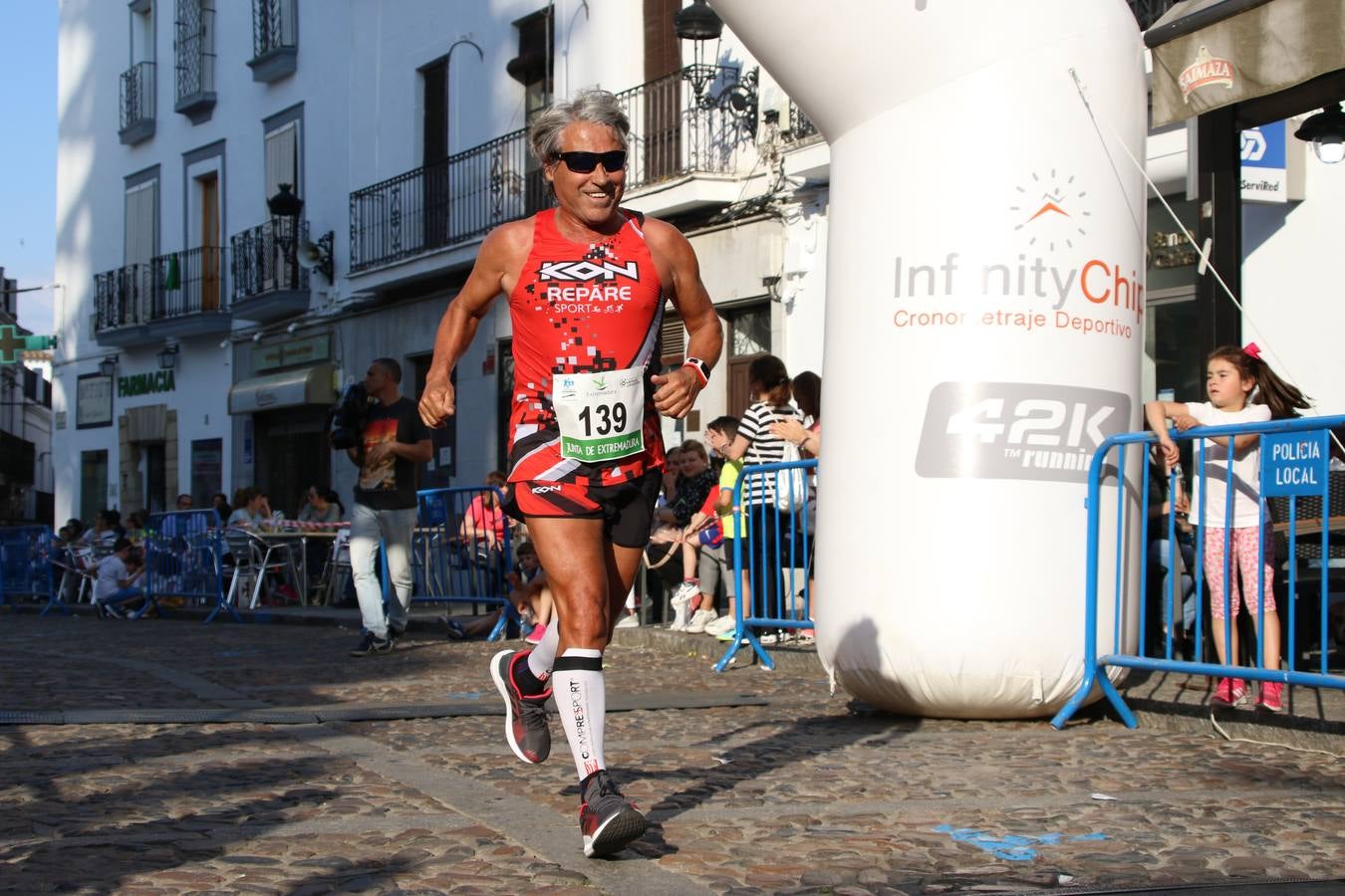 La Plaza de España de Jerez de los Caballeros acogió, ayer, la XXI Carrera Popular y VIII Caminata por la Salud y Solidaridad, organizada por la Concejalía de Juventud y Deportes del Ayuntamiento de Jerez con el apoyo del Programa de Dinamización Deportiva de la Mancomunidad Sierra Suroeste. Esta edición congregó a más de 250 participantes entre todas las categorías y se recaudaron 84 kilos de alimentos y 75 euros destinados a Cruz Roja en Jerez. La citada prueba se consagra, año tras año, como una de las citas deportivas ineludibles y más esperadas por los jerezanos y jerezanas. 