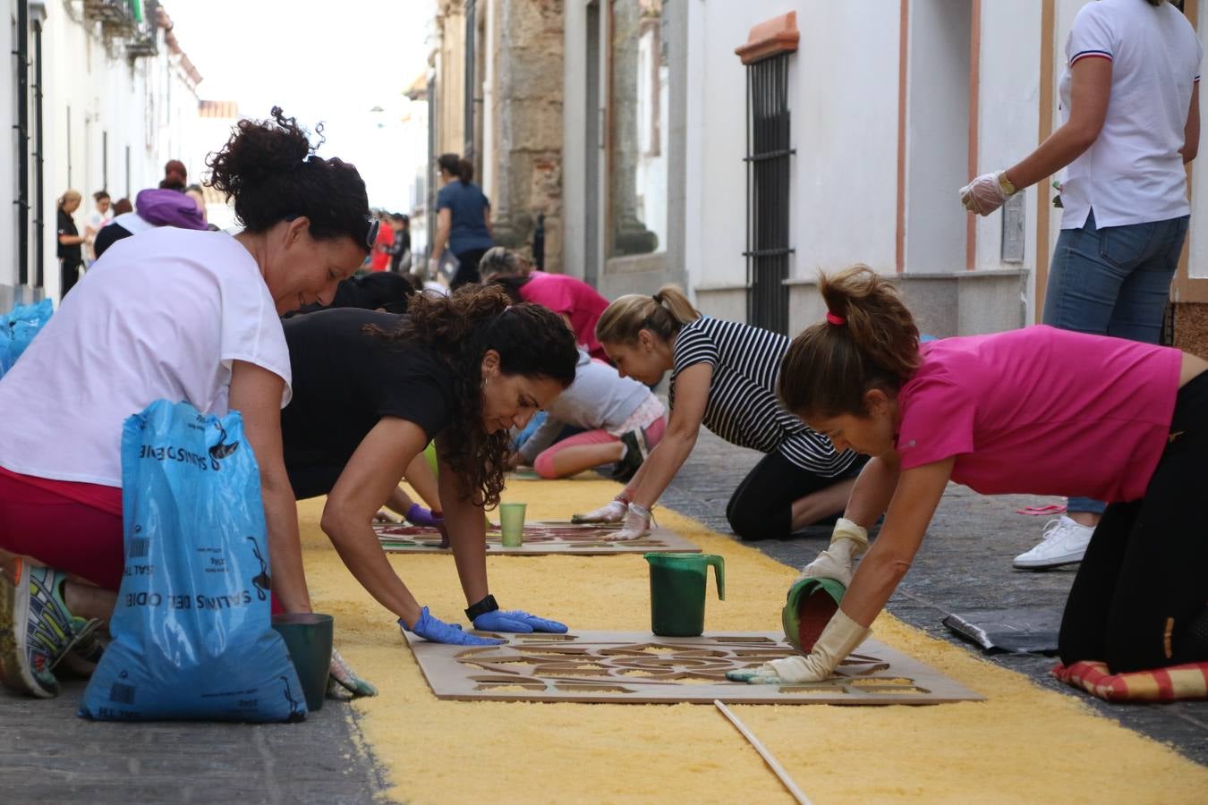 Las alfombras de sal embellecen y llenan de color, hoy, las calles de Jerez de los Caballeros con motivo de la festividad del Corpus Christi. Desde primera hora de la mañana, miembros de las cofradías y hermandades, Cáritas, grupos de catequesis, familias de los niños que han hecho este año la Primera Comunión, miembros de la Asociación de costaleros y costaleras de la Semana Santa jerezana, Ayuntamiento y vecinos han cubierto las principales calles del municipio con 6.250 kilos de sal teñida, plenas de color. A continuación, han disfrutado de una jornada de convivencia en la Casa de la Iglesia 'Cecilia de Arteaga'.