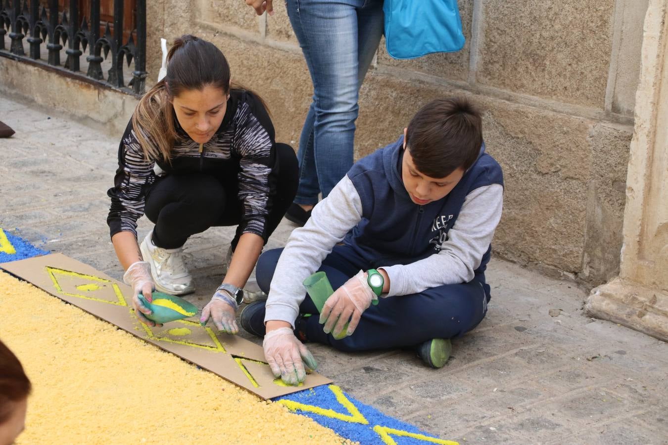 Las alfombras de sal embellecen y llenan de color, hoy, las calles de Jerez de los Caballeros con motivo de la festividad del Corpus Christi. Desde primera hora de la mañana, miembros de las cofradías y hermandades, Cáritas, grupos de catequesis, familias de los niños que han hecho este año la Primera Comunión, miembros de la Asociación de costaleros y costaleras de la Semana Santa jerezana, Ayuntamiento y vecinos han cubierto las principales calles del municipio con 6.250 kilos de sal teñida, plenas de color. A continuación, han disfrutado de una jornada de convivencia en la Casa de la Iglesia 'Cecilia de Arteaga'.