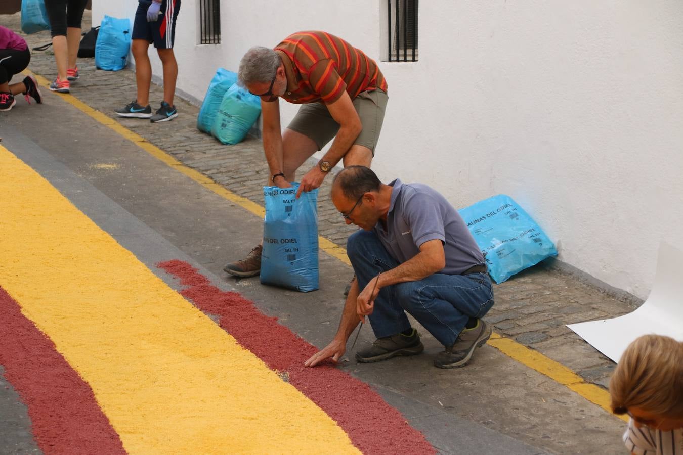 Las alfombras de sal embellecen y llenan de color, hoy, las calles de Jerez de los Caballeros con motivo de la festividad del Corpus Christi. Desde primera hora de la mañana, miembros de las cofradías y hermandades, Cáritas, grupos de catequesis, familias de los niños que han hecho este año la Primera Comunión, miembros de la Asociación de costaleros y costaleras de la Semana Santa jerezana, Ayuntamiento y vecinos han cubierto las principales calles del municipio con 6.250 kilos de sal teñida, plenas de color. A continuación, han disfrutado de una jornada de convivencia en la Casa de la Iglesia 'Cecilia de Arteaga'.