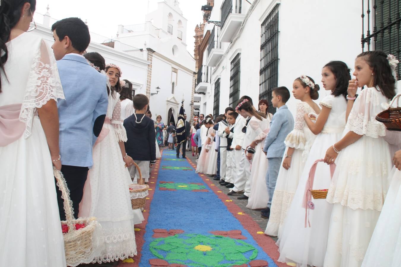 Jerez de los Caballeros celebró ayer la festividad del Corpus Christi en medio de un ambiente de solemnidad y convivencia del que fueron partícipes cientos de personas.La iglesia visigoda de Santa María de la Encarnación, llena de fieles, acogió la celebración de la Eucaristía que dió paso a la procesión acompañando la Santa Custodia en el magnífico templete de la iglesia de San Miguel, sobre las andas de la Virgen de Aguasantas y portada por costaleros y costaleras de la recién Asociación creada en esta ciudad. El párroco, Antonio María Rejano, destacó la significación de esta procesión, lamás grande, dijo, «porque Jesús sale a nuestras vidas, a nuestro encuentro y nosotros le acompañamos». Al término de la misa, incidió en el agradecimiento a todas las personas que han participado para hacer posible su desarrollo, trabajando desde la jornada del sábado en la elaboración de las preciosas alfombras de sal teñida de colores, que lucieron en las calles del centro de Jerez. El agradecimiento fue especial para los padres y madres de los niños y niñas que han hecho la Primera Comunión, para éstos mismos, también para catequistas, Cofradías y Hermandades, la Asociación del costaleros y costaleras de la Semana Santa de Jerez de los Caballeros, Ayuntamiento, Policía Local, grupos y personas de la parroquia.Autoridades civiles en representación del Ayuntamiento, Policía Local y Guardia Civil, acompañaron el desarrollo de la procesión junto a representantes de todas las cofradías y hermandades jerezanas y el protagonismo de los más de 80 niños y niñas que este año han celebrado su Primera Comunión.  A lo largo de todo el recorrido se instalaron distintos altares, también con la colaboración de vecinos y centros como la Residencia de Mayores Hernando de Soto. Los magníficos sones de la Agrupación Musical 'Nuestro Padre Jesús Nazareno' coronaron esta hermosa procesión.