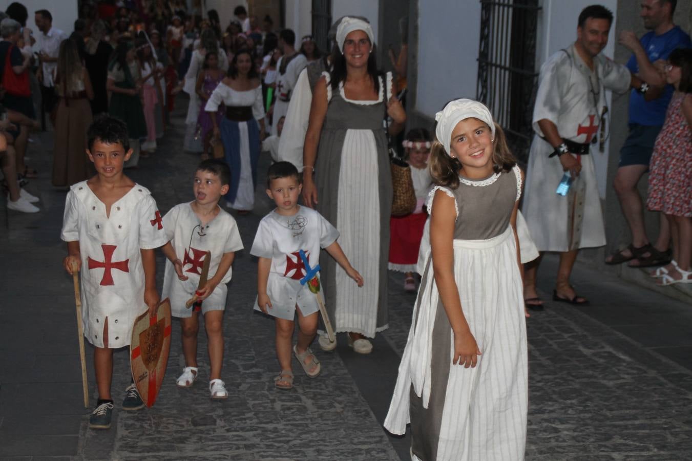 La participación popular fue nuevo protagonista del desfile teatralizado que anoche inauguró el grueso de la programación del XVI Festival Templario, invitando a propios y visitantes a revivir un pasado de leyenda, concretamente el siglo en el que La Orden del Temple marcó la vida de esta ciudad, en la que tuvo una de sus principales Encomiendas, siendo además el último reducto de Los Templarios en los reinos de España.La Asociación juvenil y cultural 'La Trouppe' estuvo al frente de la coordinación de dicho desfile que llenó de ambiente y animación las calles y plazas del centro histórico de Jerez de los Caballeros, llenas de público y engalanadas para la ocasión con pendones con la cruz templaria y otros elementos referentes a la cultura árabe que dejó su impronta en aquella época. Destacó la participación de más de 60 niñas que pusieron alegría con sus bailes a este pasacalle, junto a personajes fantásticos en zancos, la melodía de la Asociación Musical de Jerez de los Caballeros y la participación de asociaciones, como la del Belén 'Santa Ángela', Euexia Rural, además de los caballeros del campamento medieval a cargo de Cabalbur y de manera especial, la implicación de numerosos vecinos de todas las edades que desfilaron ataviados con indumentaria de la época dando vida a esta celebración.