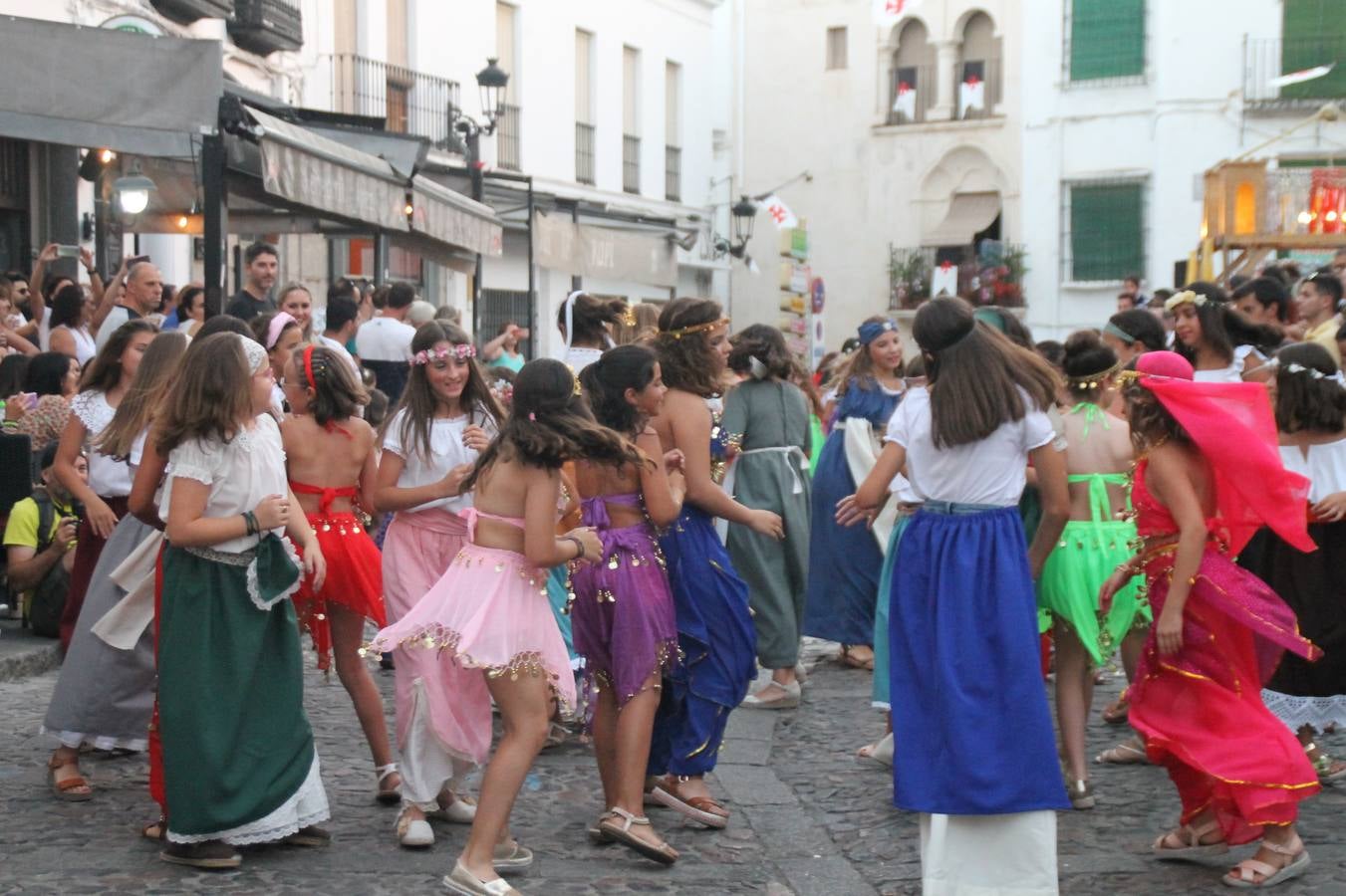La participación popular fue nuevo protagonista del desfile teatralizado que anoche inauguró el grueso de la programación del XVI Festival Templario, invitando a propios y visitantes a revivir un pasado de leyenda, concretamente el siglo en el que La Orden del Temple marcó la vida de esta ciudad, en la que tuvo una de sus principales Encomiendas, siendo además el último reducto de Los Templarios en los reinos de España.La Asociación juvenil y cultural 'La Trouppe' estuvo al frente de la coordinación de dicho desfile que llenó de ambiente y animación las calles y plazas del centro histórico de Jerez de los Caballeros, llenas de público y engalanadas para la ocasión con pendones con la cruz templaria y otros elementos referentes a la cultura árabe que dejó su impronta en aquella época. Destacó la participación de más de 60 niñas que pusieron alegría con sus bailes a este pasacalle, junto a personajes fantásticos en zancos, la melodía de la Asociación Musical de Jerez de los Caballeros y la participación de asociaciones, como la del Belén 'Santa Ángela', Euexia Rural, además de los caballeros del campamento medieval a cargo de Cabalbur y de manera especial, la implicación de numerosos vecinos de todas las edades que desfilaron ataviados con indumentaria de la época dando vida a esta celebración.