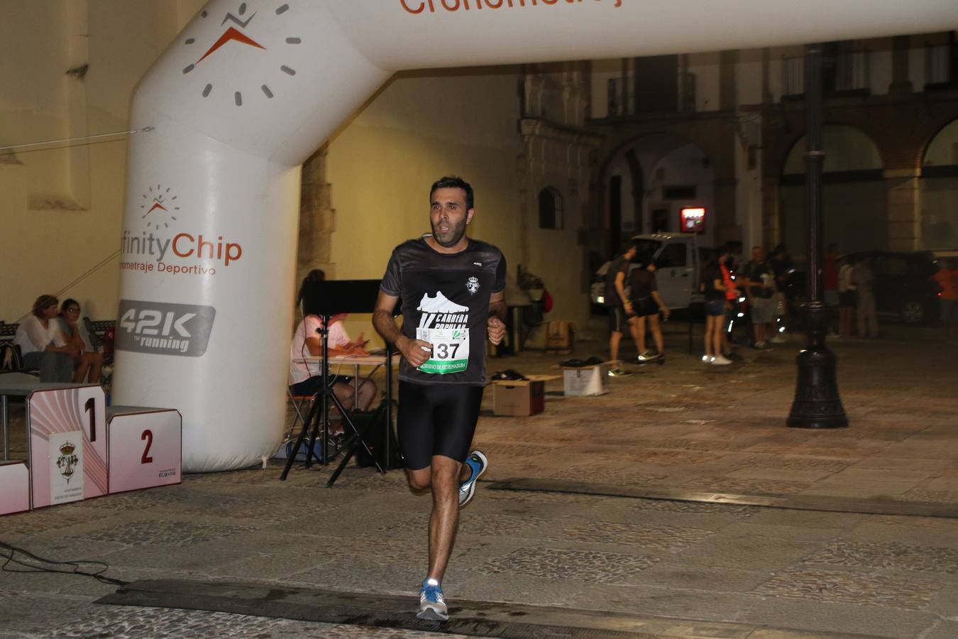 La Plaza de España de Jerez de los Caballeros acogió, ayer, la V Carrera Popular Nocturna 'Recorriendo el Medievo', organizada por el Ayuntamiento del municipio con la colaboración del Plan de Dinamización Deportiva de la Mancomunidad Sierra Suroeste. Las principales calles del municipio volvieron a convertirse en el mejor escenario para el desarrollo de esta prueba deportiva que, año tras año, se consolida como una de las citas más destacadas del calendario estival jerezano y en la que la solidaridad, también, está muy presente. Así, se lograron recaudar 153 kilos y 22 euros que irán destinados al almacén de alimentos que gestiona la Asamblea local de Cruz Roja en el municipio.En esta edición, han participado unos 200 corredores de la localidad y alrededores, siendo Manuel Gómez Lucas y Tina María Ramos, vencedores de la clasificación general.