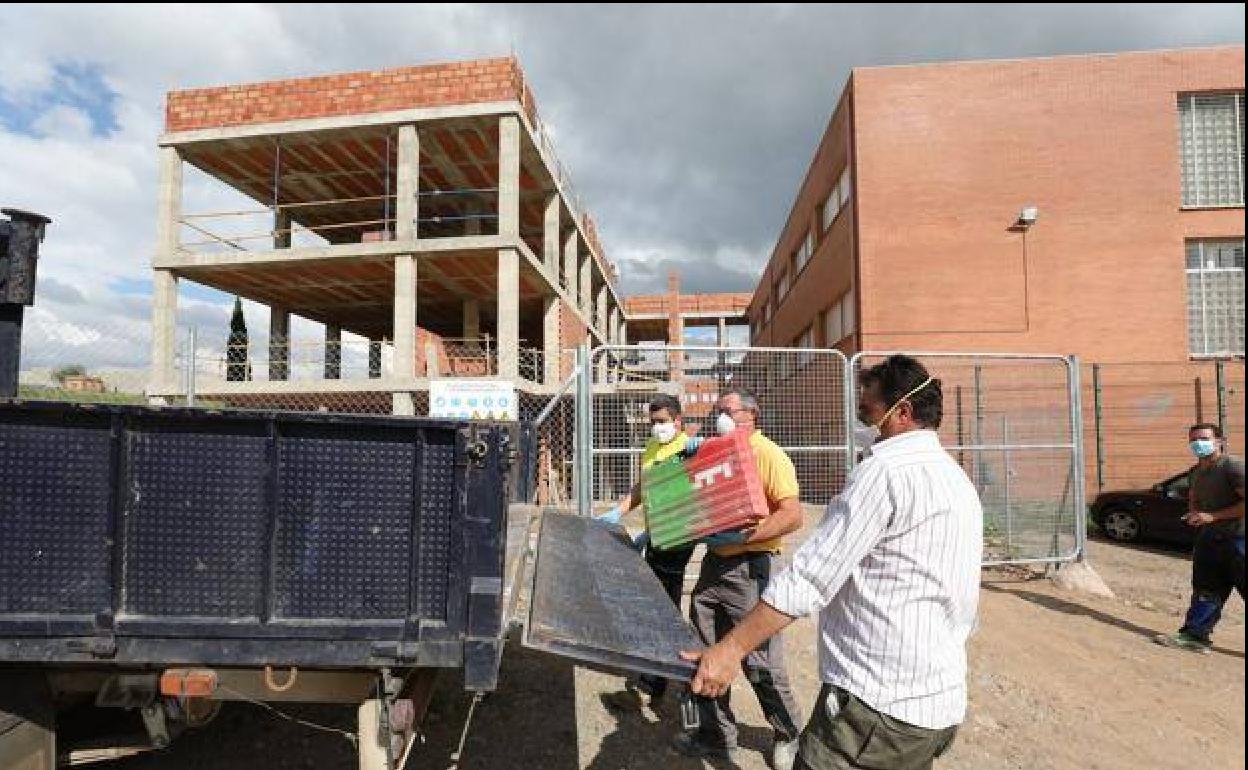 Trajadores en la obra del instituto Albarregas de Mérida recogiendo material al terminar la jornada, este lunes. 