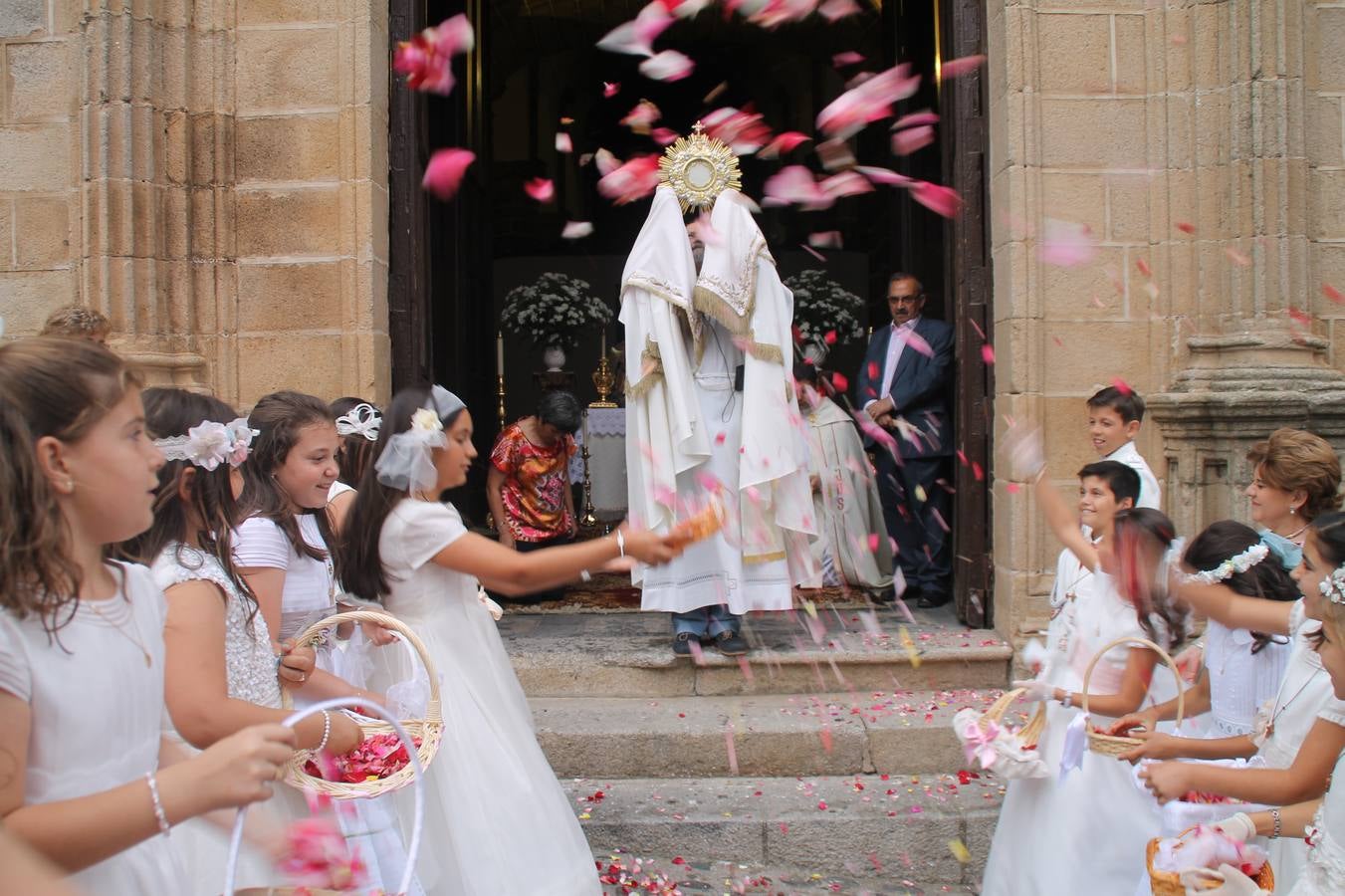 Los niños de Primera Comunión realzan la exposición del Cuerpo de Cristo ante los altareslos, lanzando pét