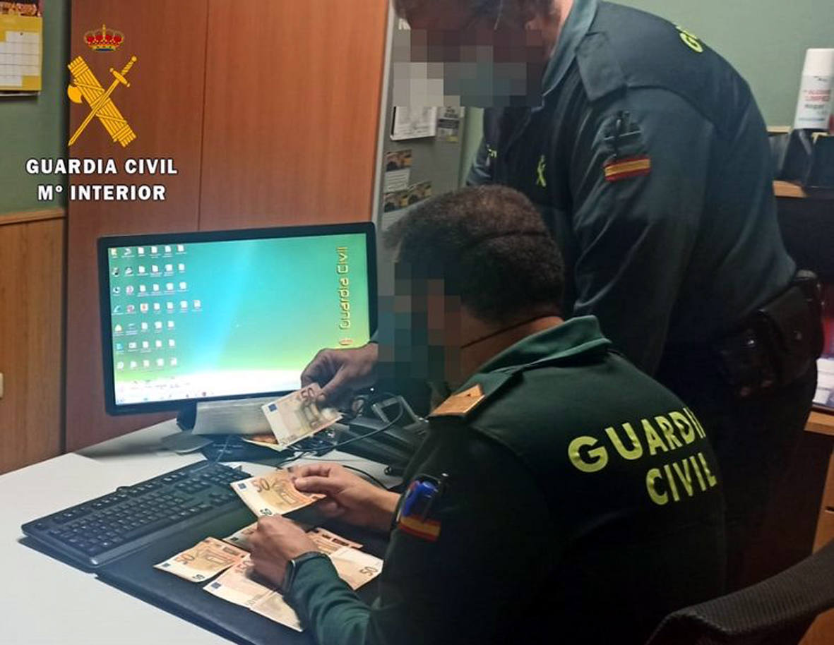 Dos agentes de la Guardia Civil con el dinero recuperado