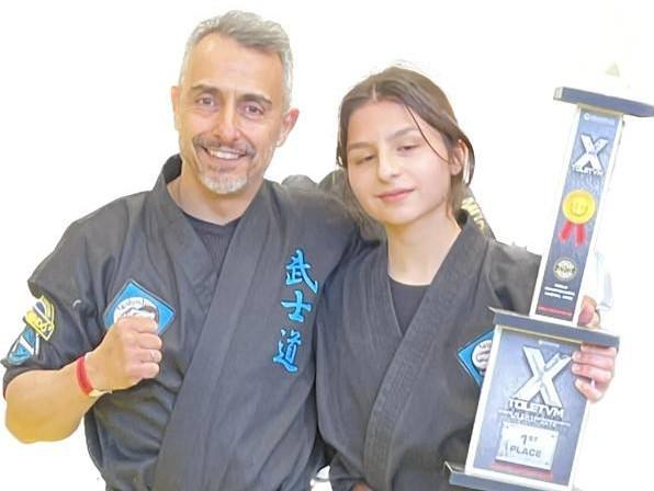 El Maestro con una de sus alumnas sosteniendo un premio