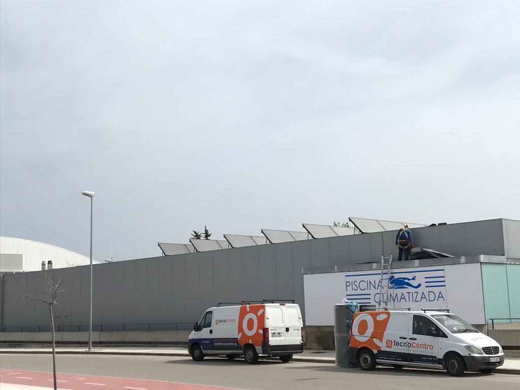 Los trabajadores instalan los paneles en la cubierta del edificio de la piscina climatizada 
