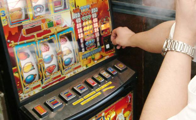 Un joven juega a una máquina en un bar. 
