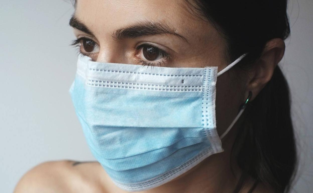 Una joven se protege con una mascarilla 