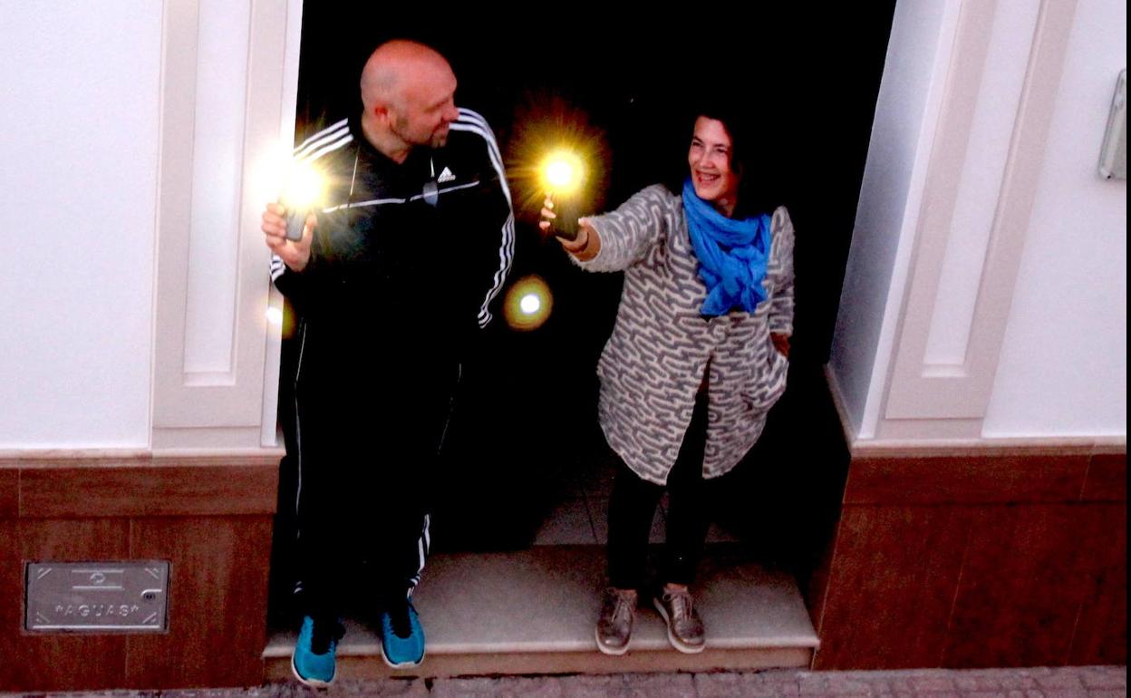 Dos vecinos de la calle Primero de Mayo alumbran con sus móviles y visten prendas de color azul. ISABEL AMBRONA