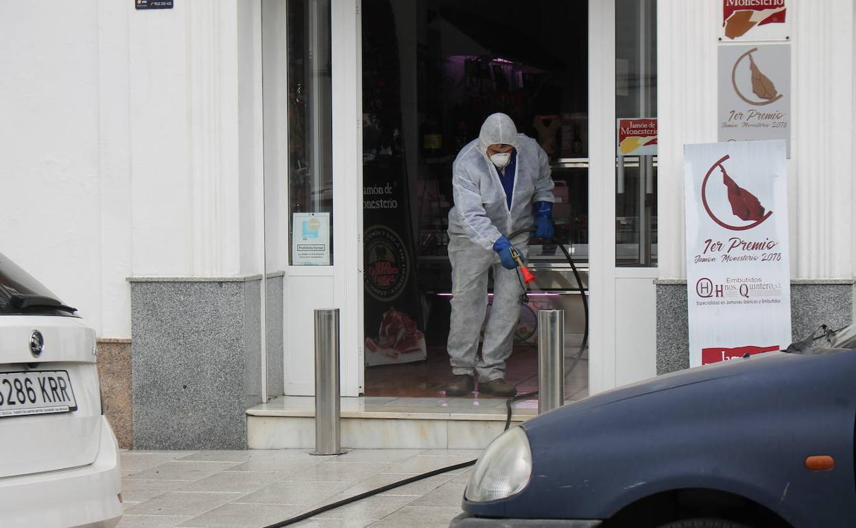 Un operario municipal desinfecta la entrada de un local comercial 