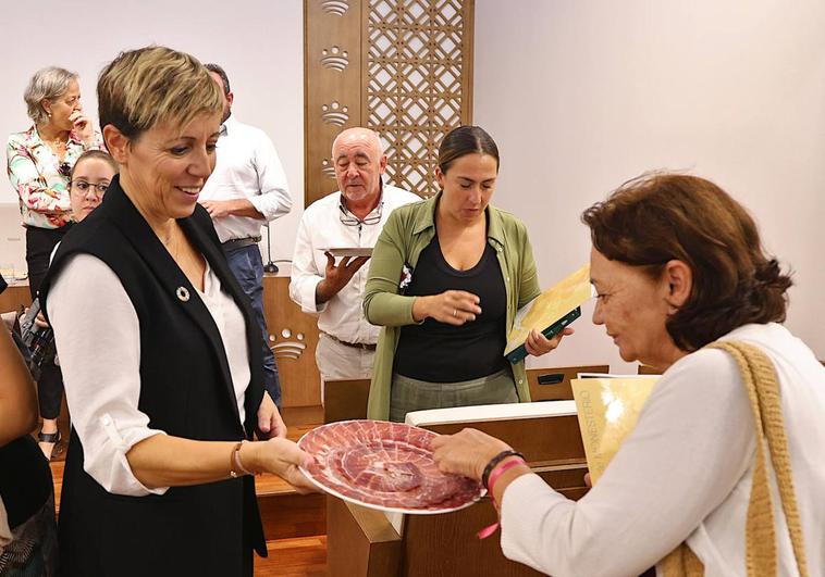 La alcaldesa de Monesterio, Loli Vargas, ofrece jamón tras la presentación de la fiesta
