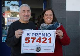Jose Granadero y Alicia González, responsable y trabajadora de la administración de Loterías, sostienen el cartel con el número del décimo premiado
