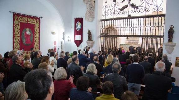 Fernández Vara con el arzobispo Celso Morga y otras autoridades ante el retablo de Pisano. Al derecha, publico de la jornada 