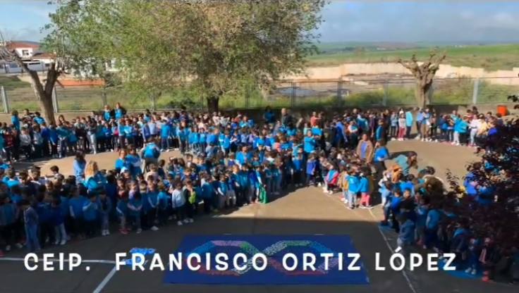 Comunidad educativa del CEIP 'Francisco Ortiz López' conformando un símbolo de infinito azul en el patio del colegio. 