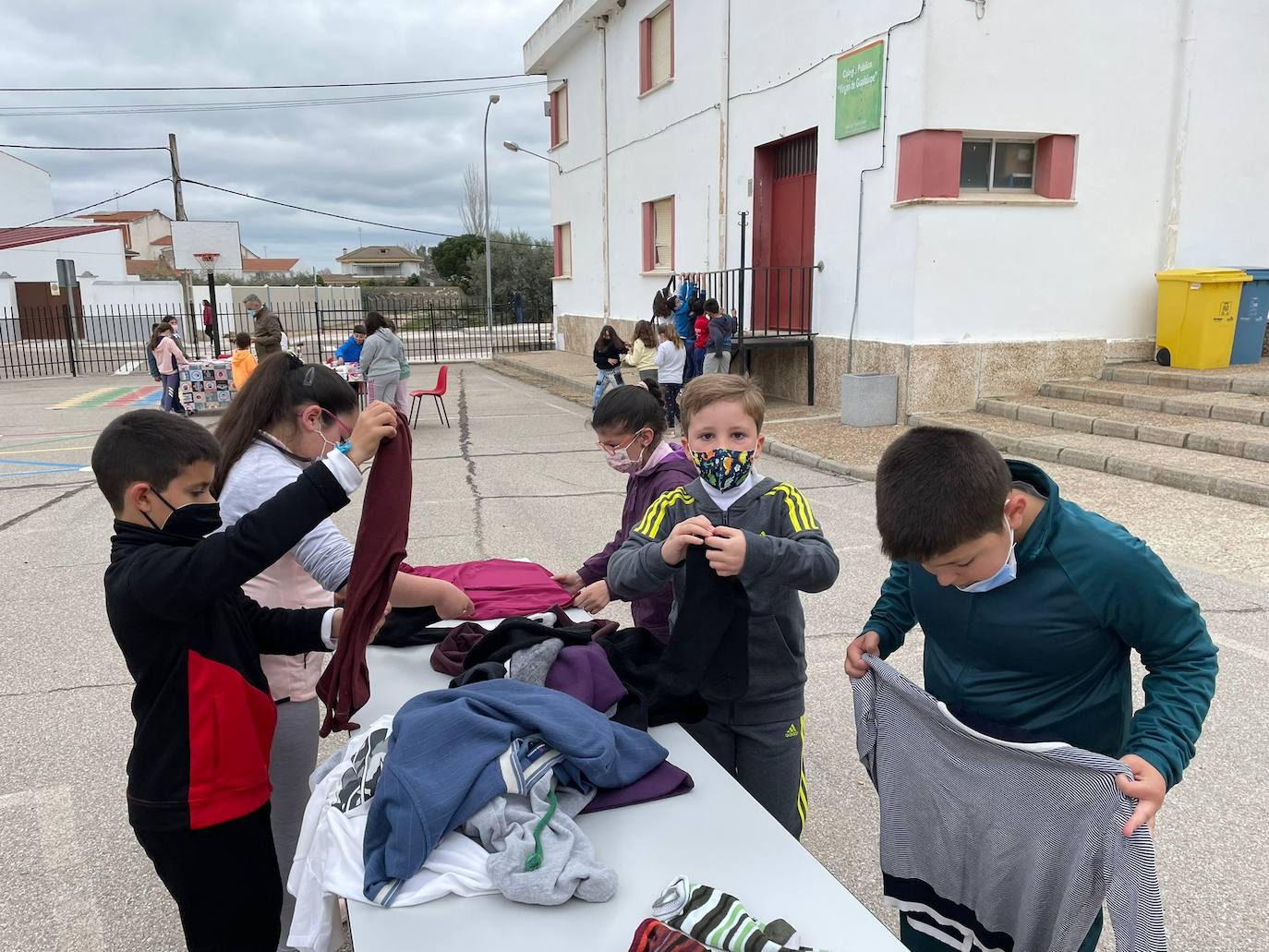 Unos alumnos doblan varias prendas de ropa 