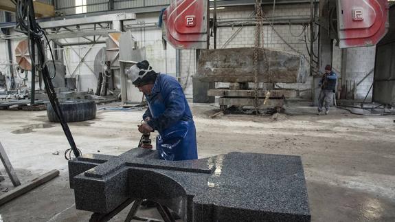 Un trabajador pule una cruz de granito 