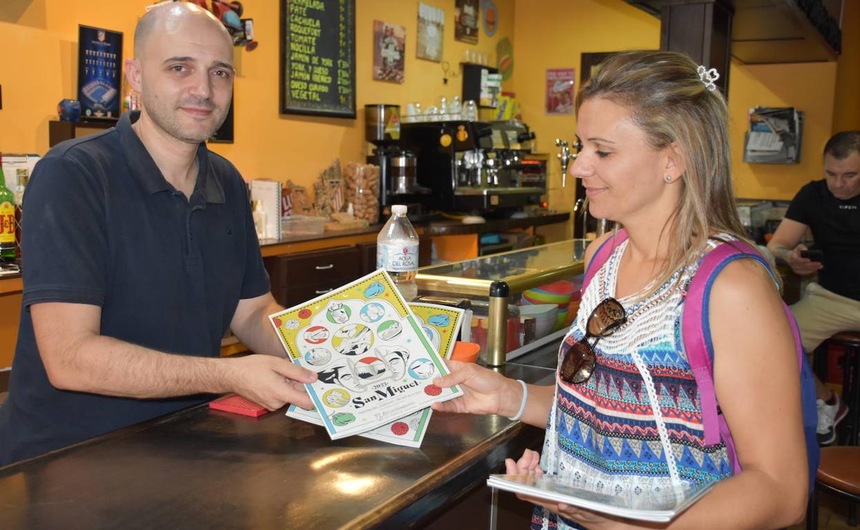 Trabajadora municipal dejando los ejemplares en el bar 'El Zaguán'. 