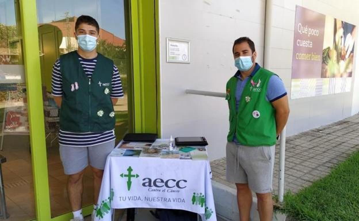 Los dos voluntgarios con la mesa informativa instalada en Jaraíz. 