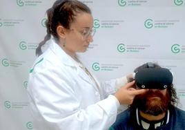 Una voluntaria coloca las gafas a un paciente