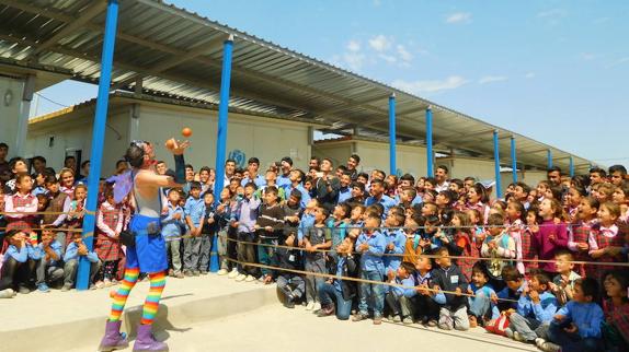 Juan Carlos Margallo haciendo malabares delante de niños y jóvenes en un campamento.